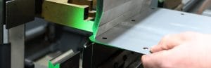 Close-up of a CNC press brake folding a sheet of metal with precision, showing laser alignment during the bending process at Riteweld Engineering.