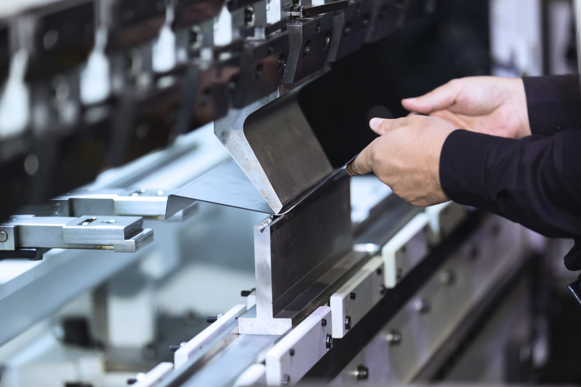 Operator bending a sheet of metal using a press brake machine at Riteweld Engineering’s facility.