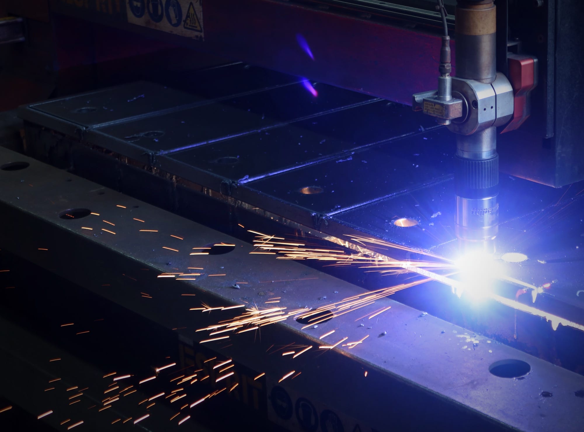 Plasma cutting machine in operation, producing sparks while cutting steel with high precision at Riteweld Engineering.