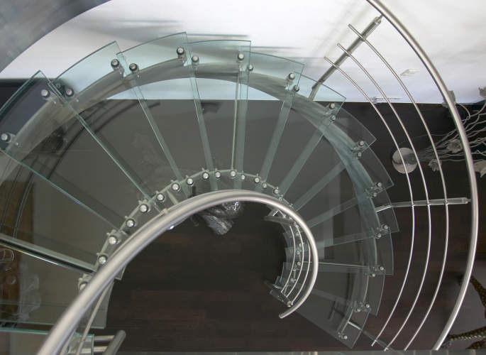 Curved staircase with glass treads, stainless steel handrails, and glass balustrades, fabricated by Riteweld Engineering.
