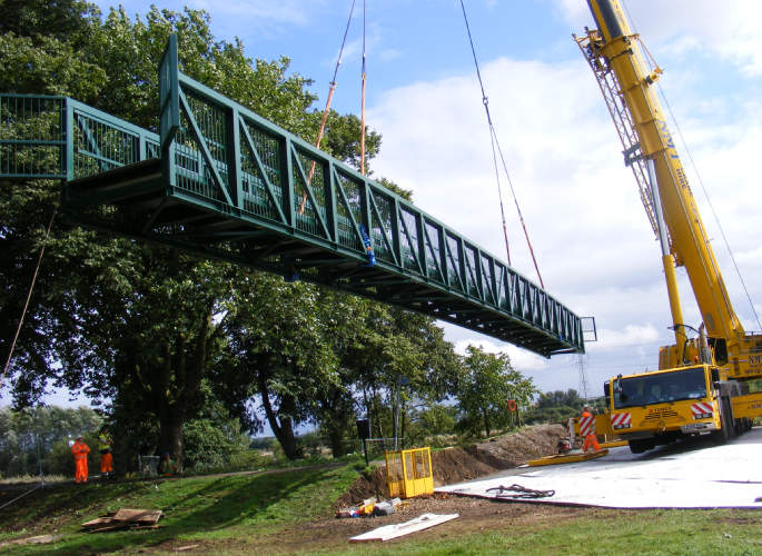Steel bridge being lifted into place by crane