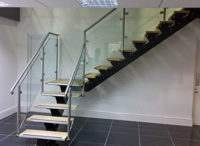 Interior staircase with open wooden treads, glass balustrades, and stainless steel handrails, fabricated by Riteweld Engineering.