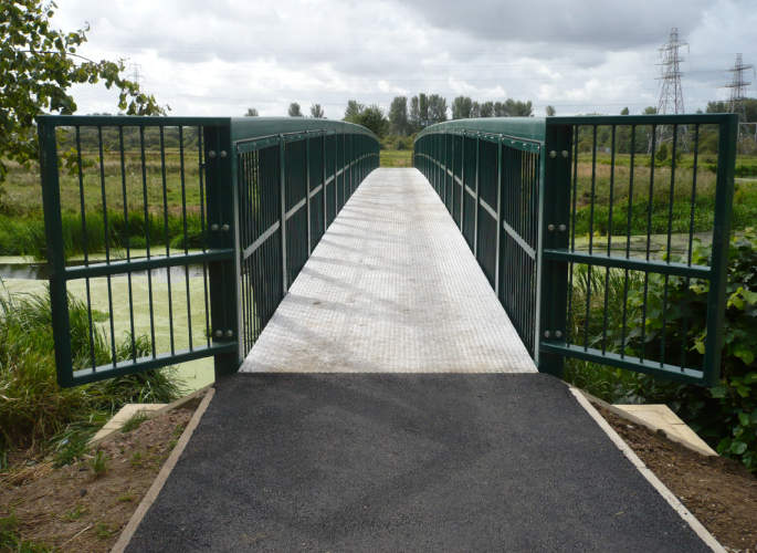 Steel pedestrian bridge spanning a river, installed in a rural location by Riteweld Engineering.