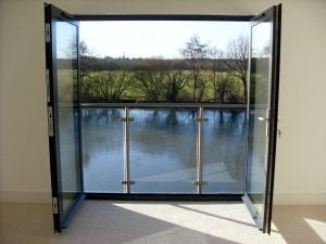 Interior view of a modern glass and steel Juliet balcony overlooking a river and countryside, designed and installed by Riteweld Engineering.