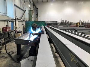 Welder fabricating a large steel beam inside a workshop at Riteweld Engineering, showcasing precision craftsmanship and structural steel expertise.
