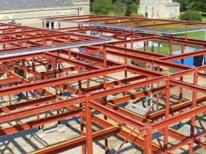 Aerial view of the structural steel grid formation at Thornton College, Oxfordshire, showing red steel beams and columns installed by Riteweld Engineering as part of a new building extension.