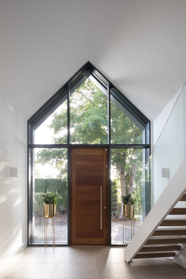 Glass balustrade installed along a modern staircase in a bright entrance hallway, with floor-to-ceiling glazing, fitted by Riteweld Engineering.