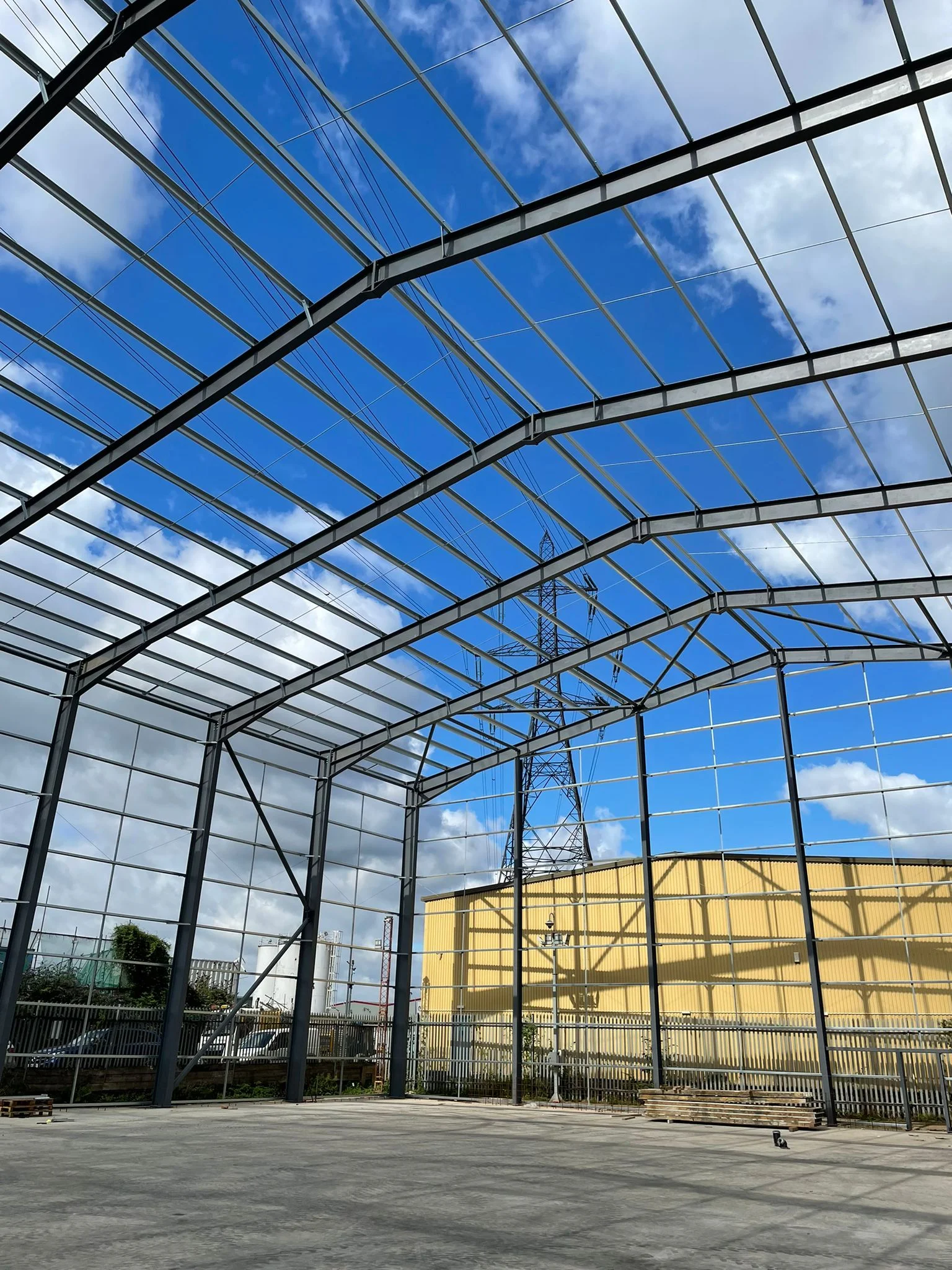 Steel frame structure under construction for an industrial building, installed by Riteweld Engineering against a clear blue sky.