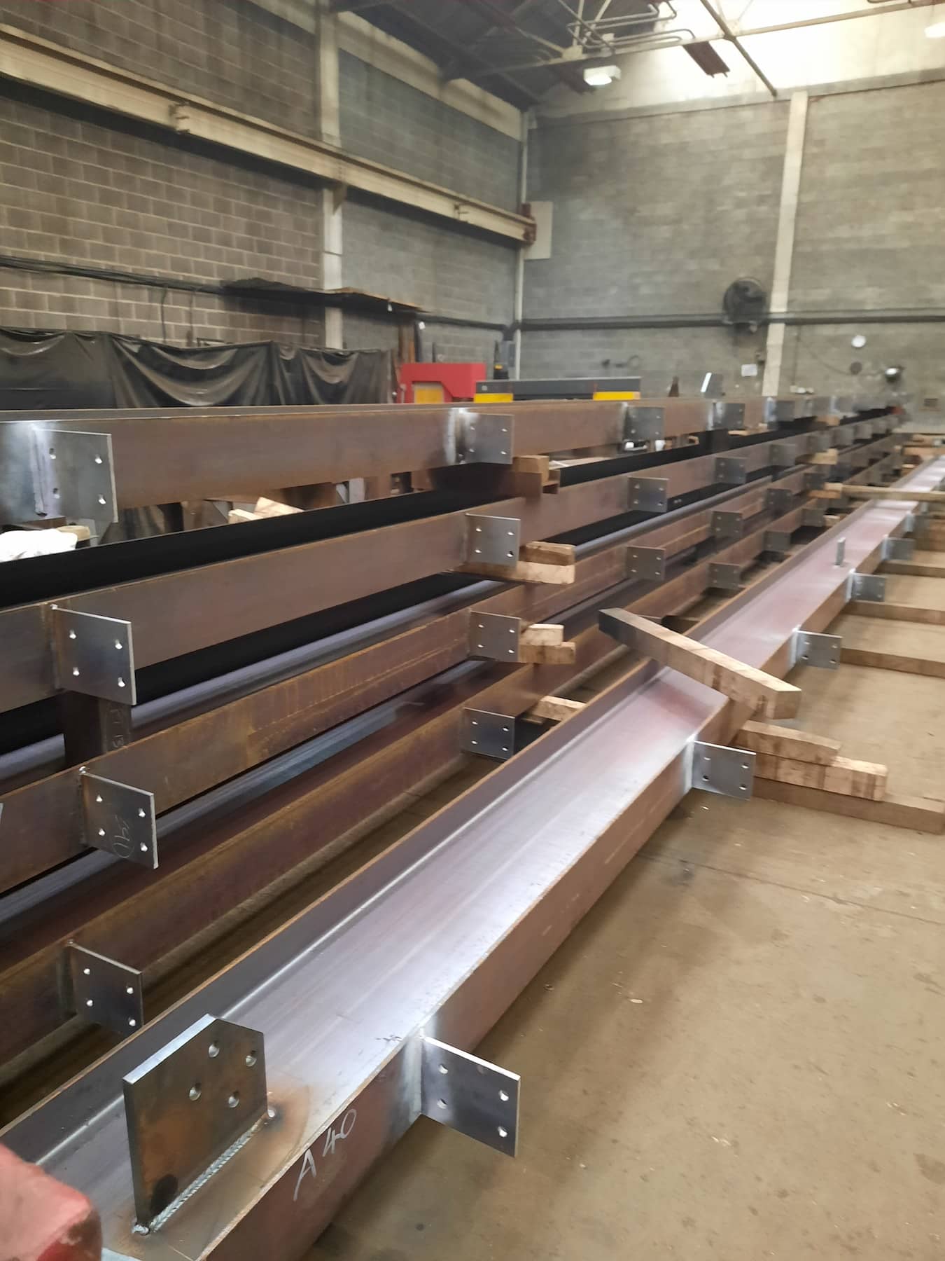 Fabricated structural steel beams stacked and prepared for delivery inside Riteweld Engineering’s workshop.