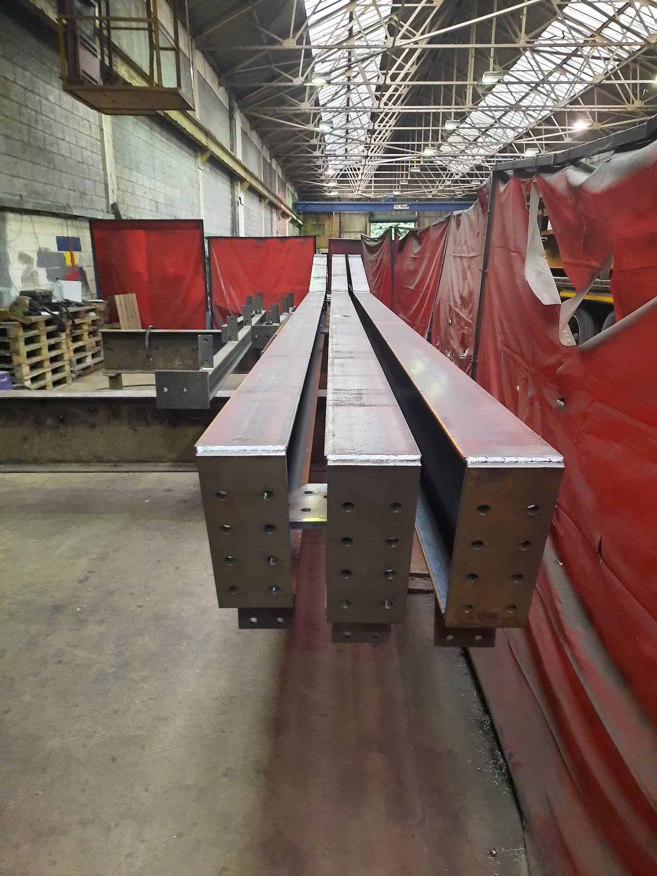 Fabricated structural steel beams lined up in a workshop, ready for inspection or further processing at Riteweld Engineering.