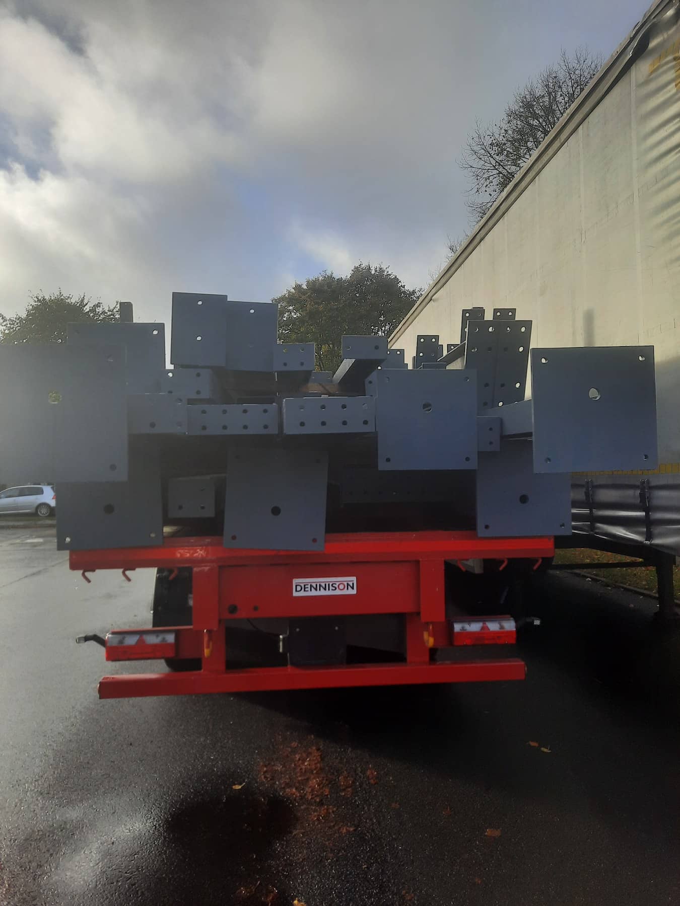 Painted structural steel components stacked on a red flatbed trailer, ready for transport from Riteweld Engineering’s facility.