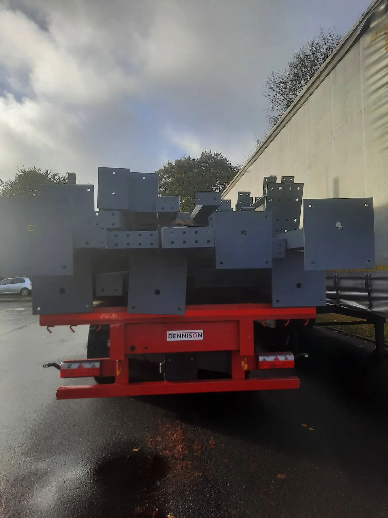 Painted structural steel components stacked on a red flatbed trailer, ready for transport from Riteweld Engineering’s facility.