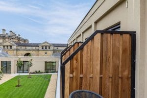 Close-up view of Canadian Red Cedar privacy screening installed on a glass-balustraded hotel balcony, with landscaped courtyard and heritage building in the background.