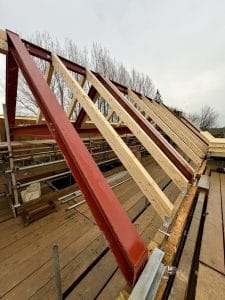 Steel roof frames with timber rafters installed on a residential construction project, forming part of a hybrid steel and engineered timber roof structure.