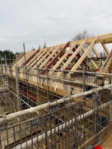 Steel roof frames and timber trusses installed on a residential construction project, forming part of a hybrid steel and engineered timber roof structure.
