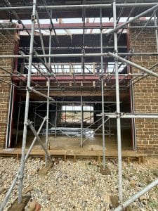 Structural steel goalpost frame installed within a residential building to support a large opening and transfer loads to the foundations.